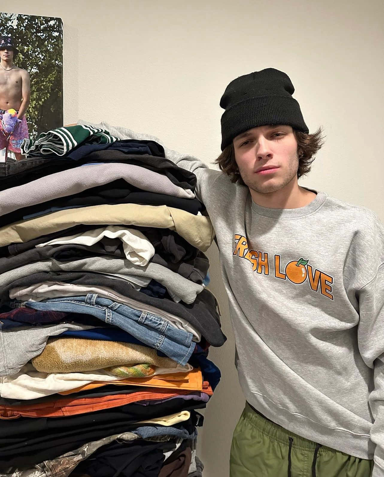 Young Man Leaningon Clothes Pile Wallpaper