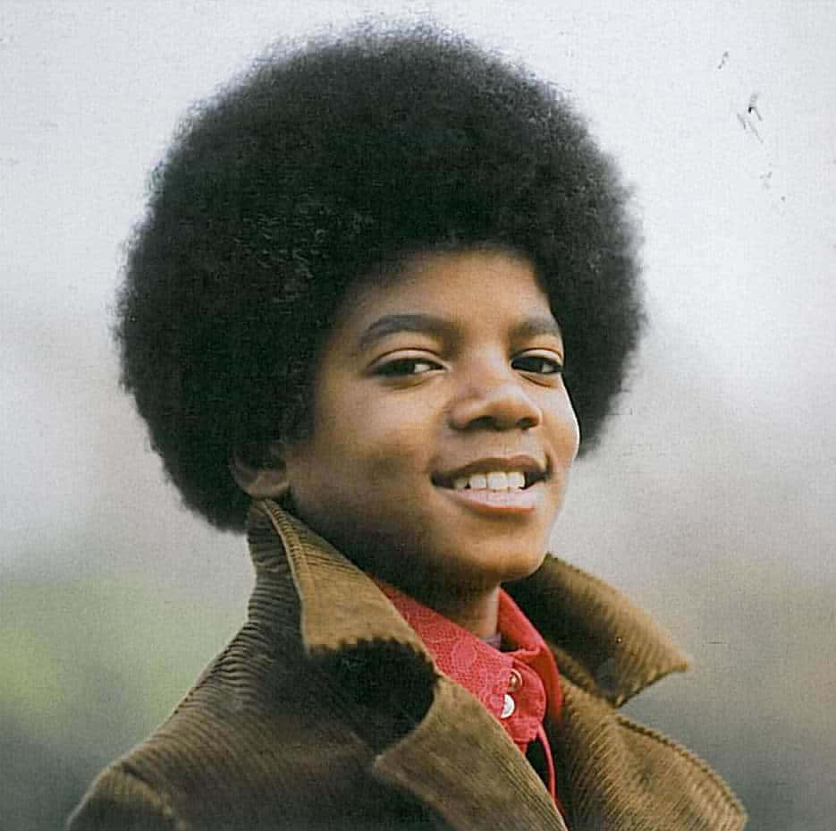 A Young Boy With An Afro Smiles For The Camera