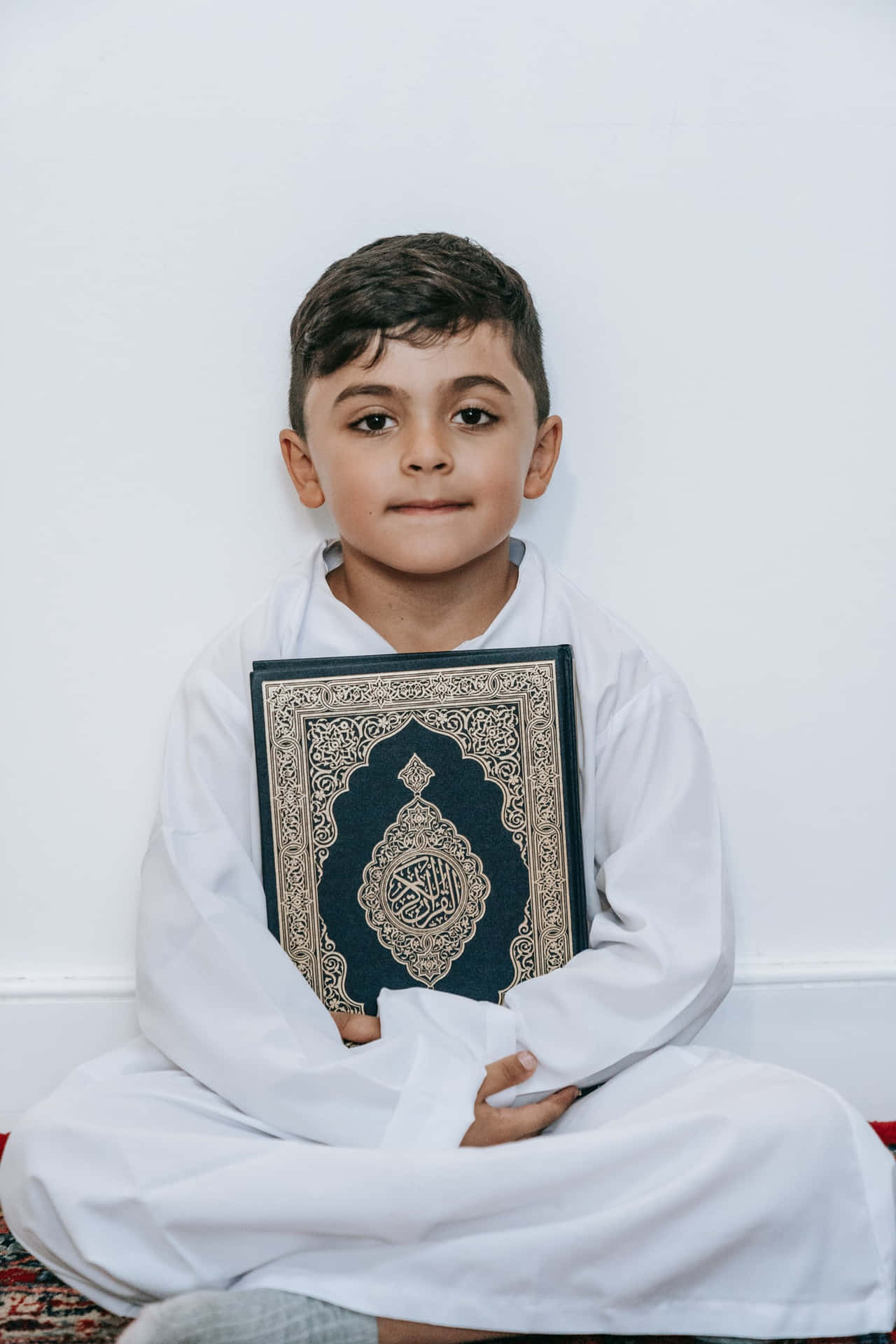 Ung muslimsk dreng, der holder Koranen bog Wallpaper