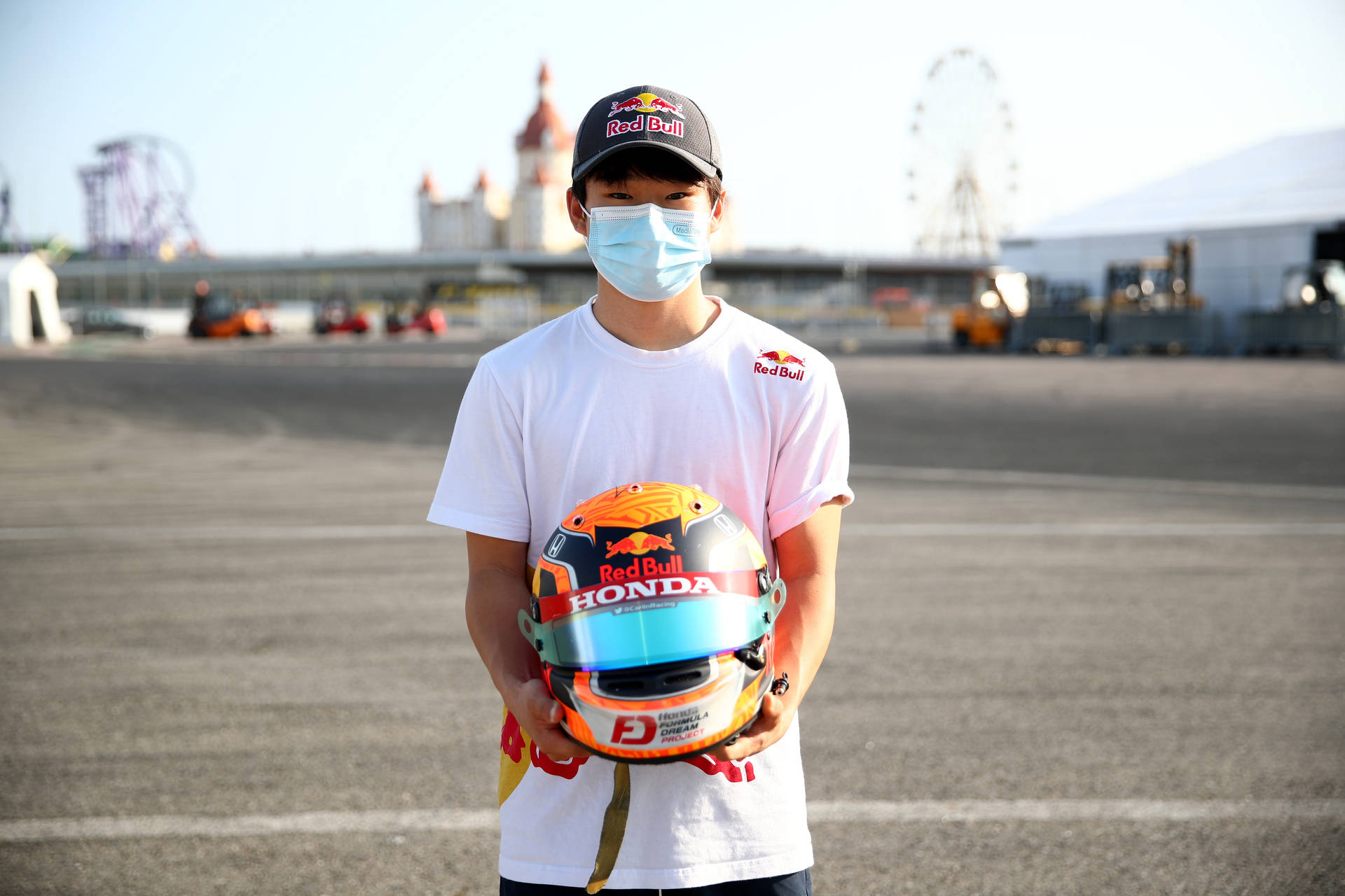 F1 Racer Yuki Tsunoda in Mask Holding Helmet Wallpaper