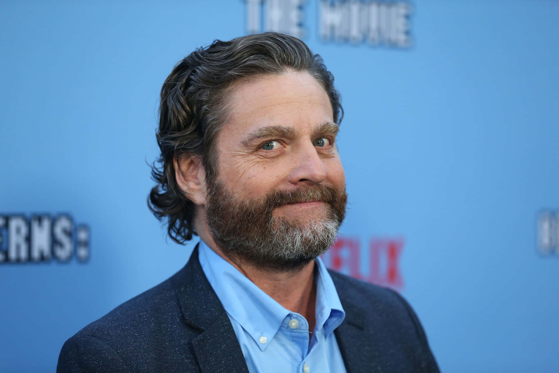 Zach Galifianakis looking pensive in a white shirt and denim jacket Wallpaper