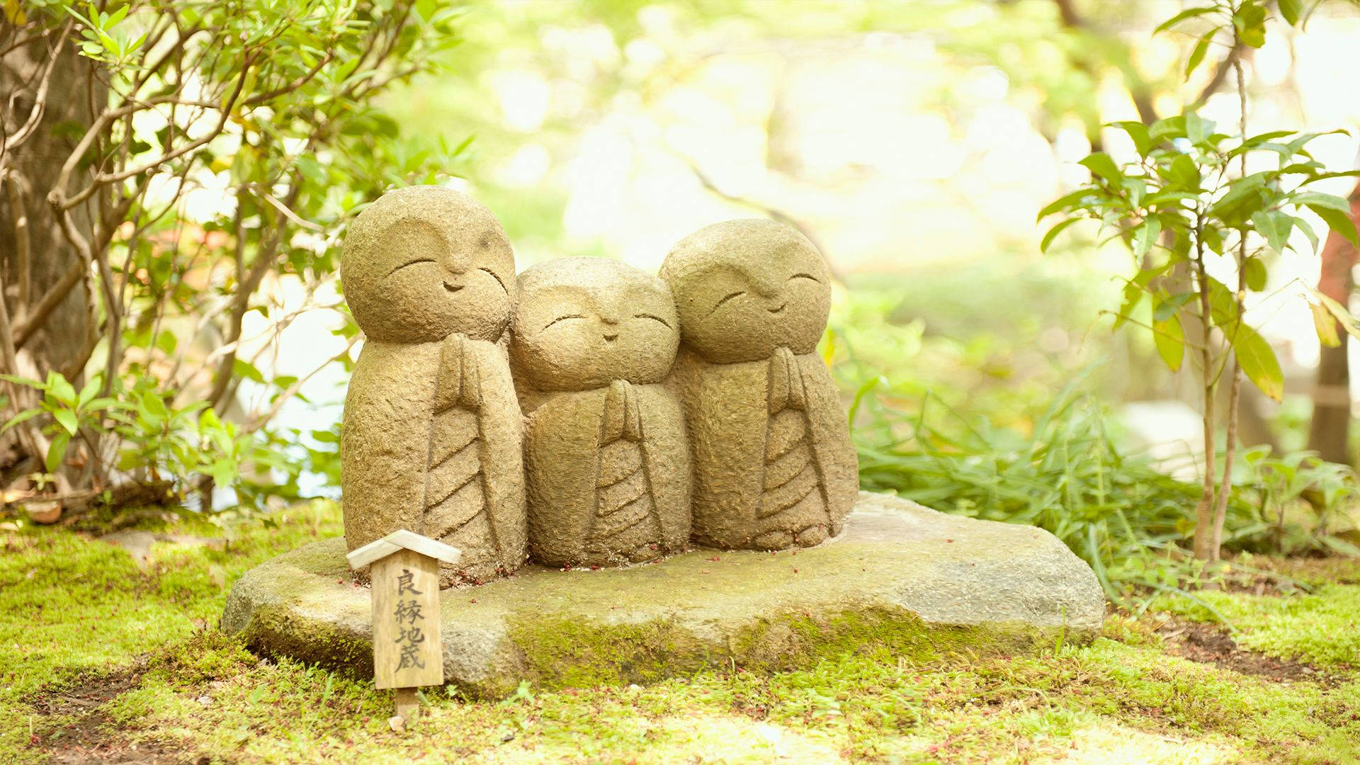Caption: Serenity In Stone - Zen Garden With Monk Statues Wallpaper