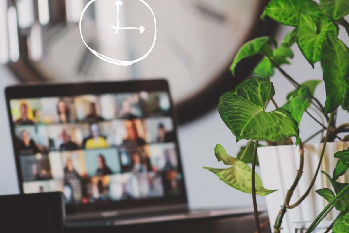 A Laptop With A Clock On It And A Plant On The Desk