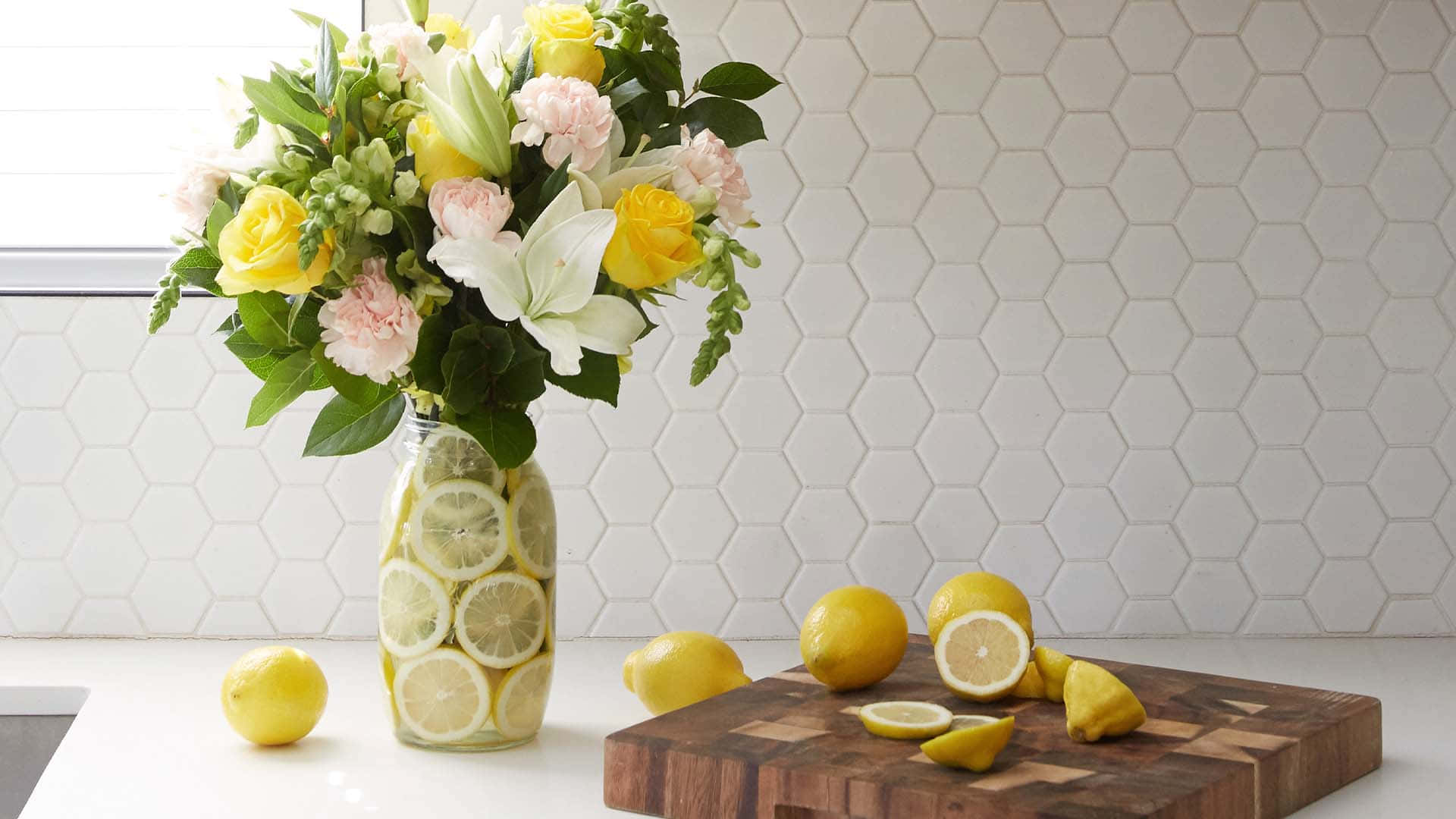 A Vase Of Flowers And Lemons On A Cutting Board