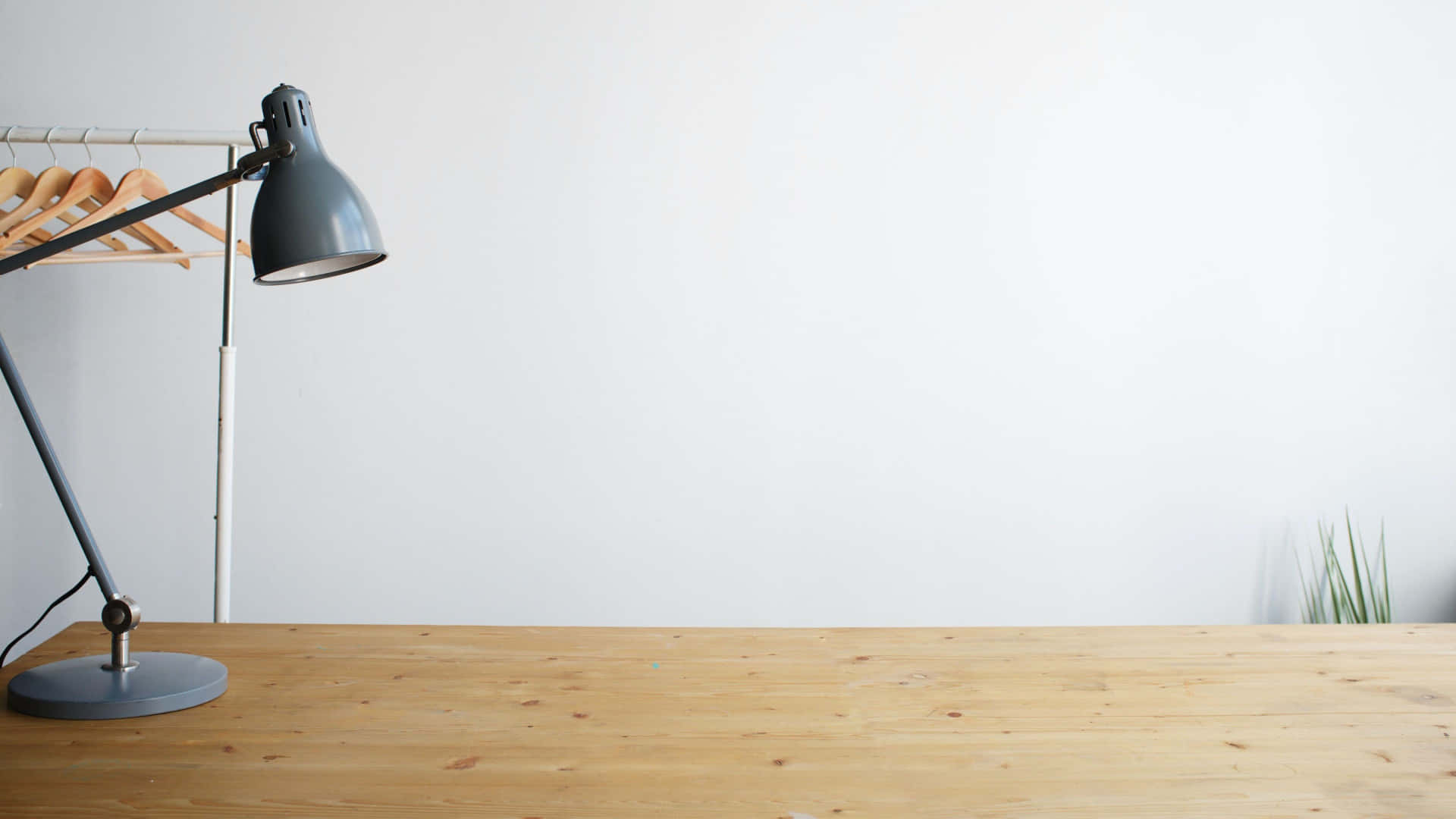 A White Wall With A Wooden Table And A Lamp