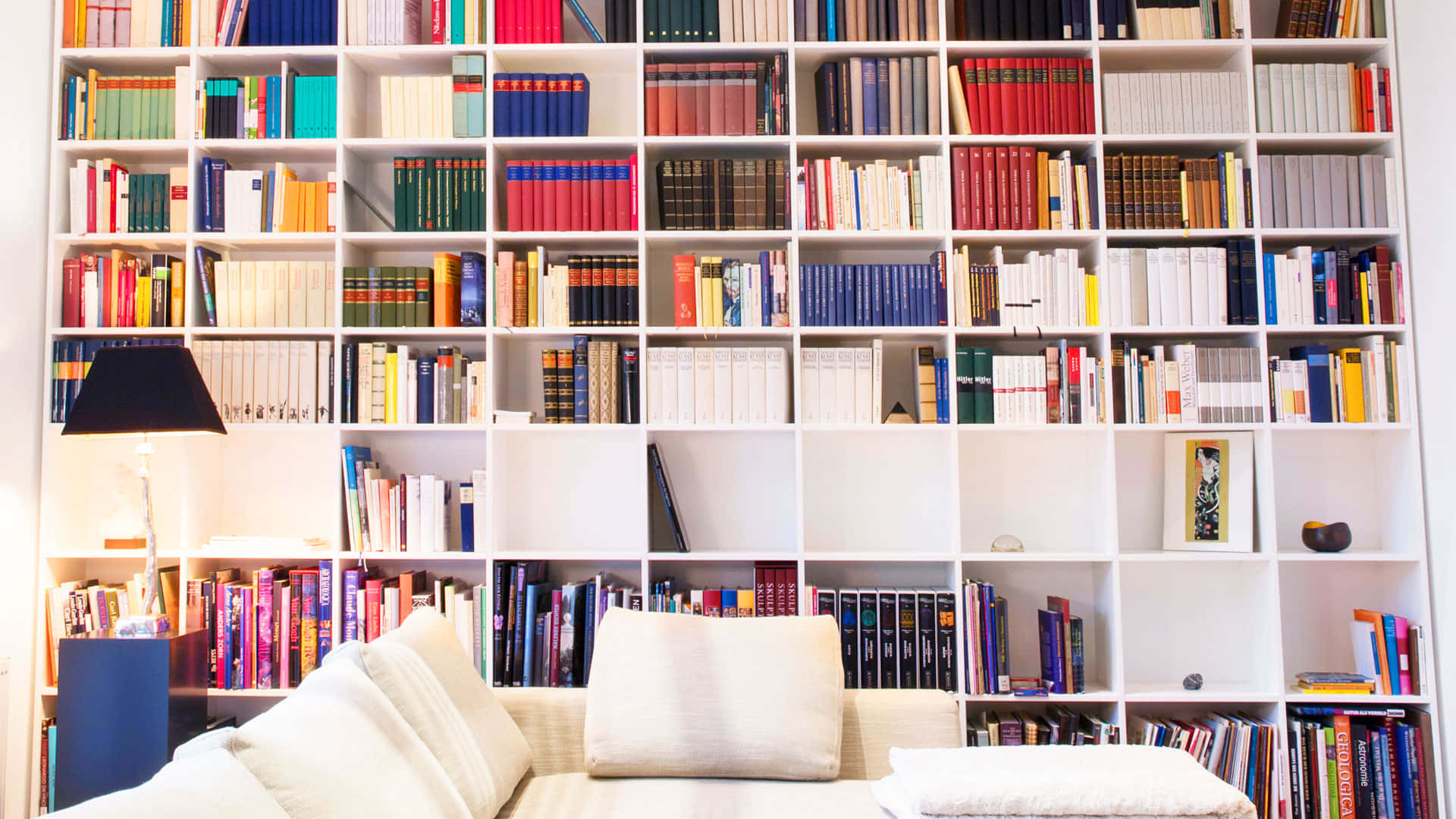 A White Couch In A Room With A White Book Shelf