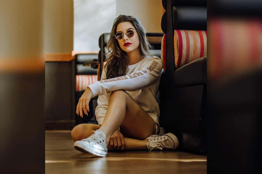 Mädchenmit Sonnenbrille in sitzender Pose Bild