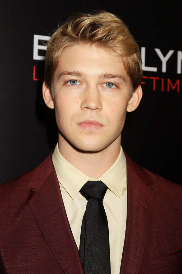 JoeAlwyn luciendo elegante en un clásico traje negro.