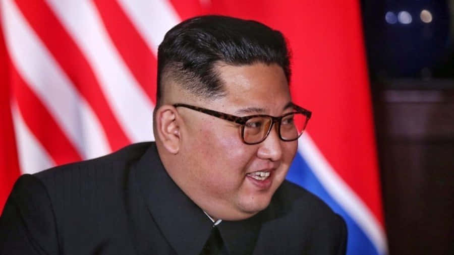 KimJong-un está sorrindo na frente das bandeiras.