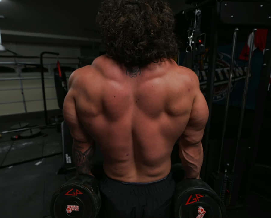 Homem Musculoso Realizando Exercício com Halteres na Academia
