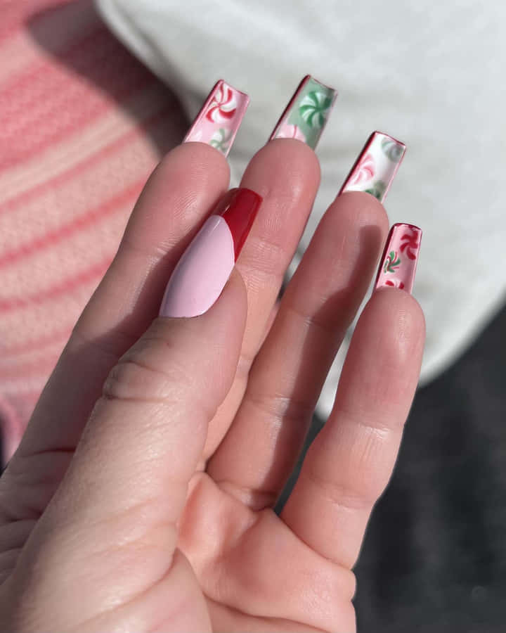Én person, der holder en pink og rød negl med blomsterdesigns