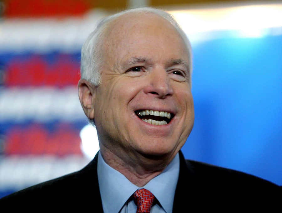 John McCain lächelnd mit amerikanischer Flagge im Hintergrund