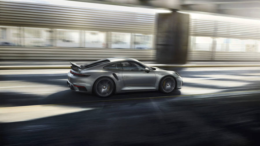 SilbernerPorsche 911 fährt neben Gebäude