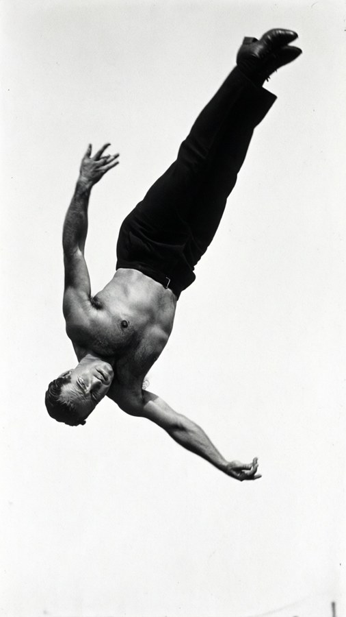 Svart-hvitt høy kontrast-bilde av Douglas Fairbanks som gjør en baklengs salto