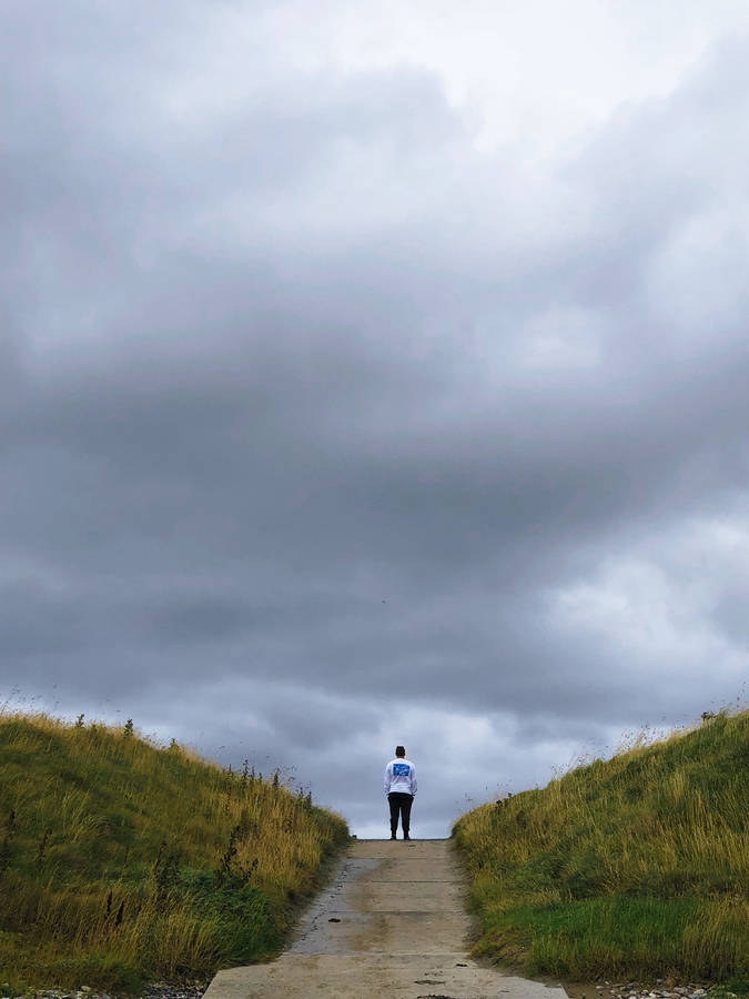 Download Alone Man Over Storm Clouds Wallpaper | Wallpapers.com