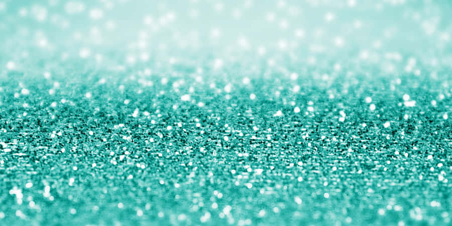 Brilhocintilante de glitter turquesa em um fundo abstrato azul e verde.