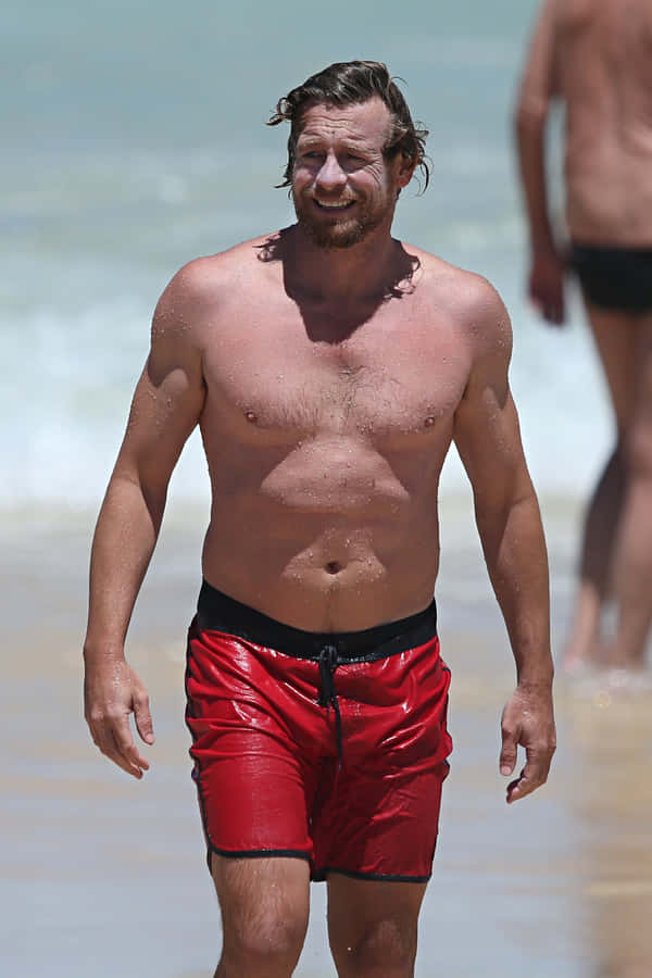 Homem Caminhando na Praia com Shorts Vermelhos