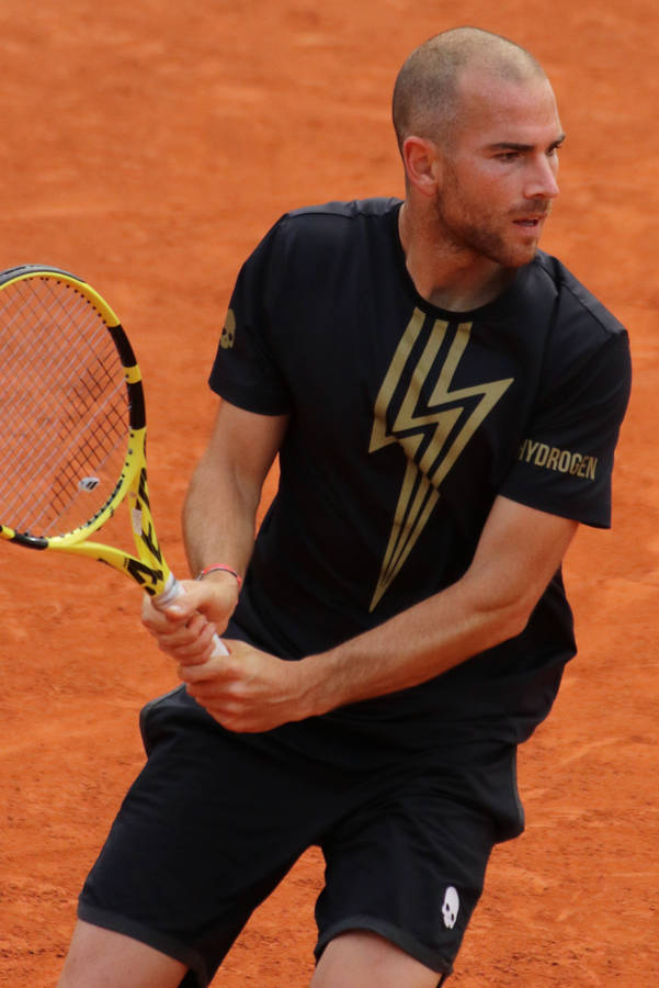 Enmand spiller tennis på en lerbane.