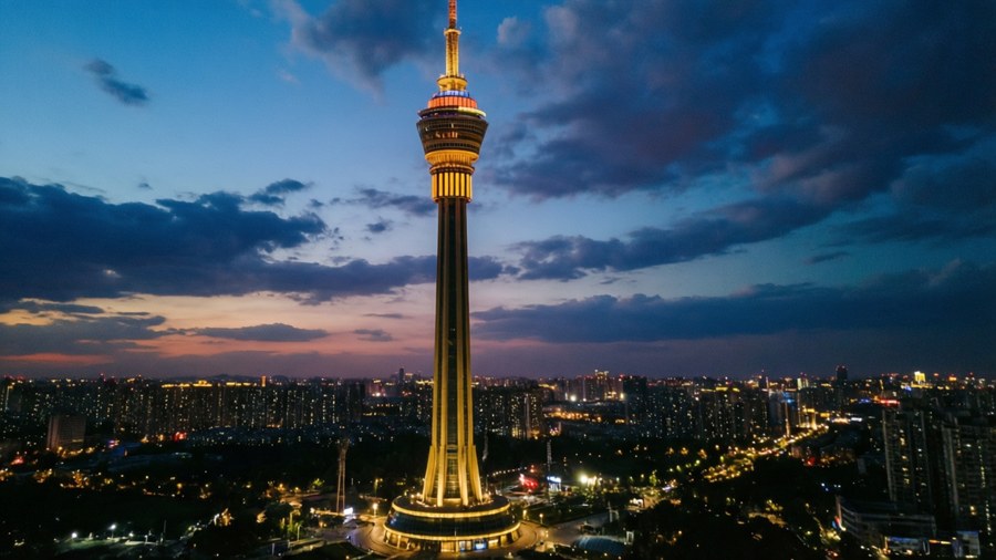 Iconic Cairo Tower glowing at dusk with a dramatic sky.