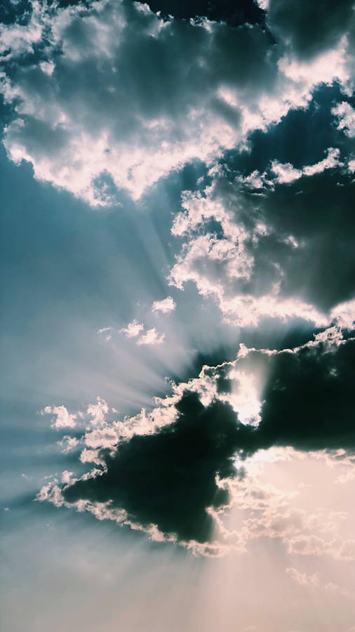 Wallpaper of dark clouds with transcending light above. 