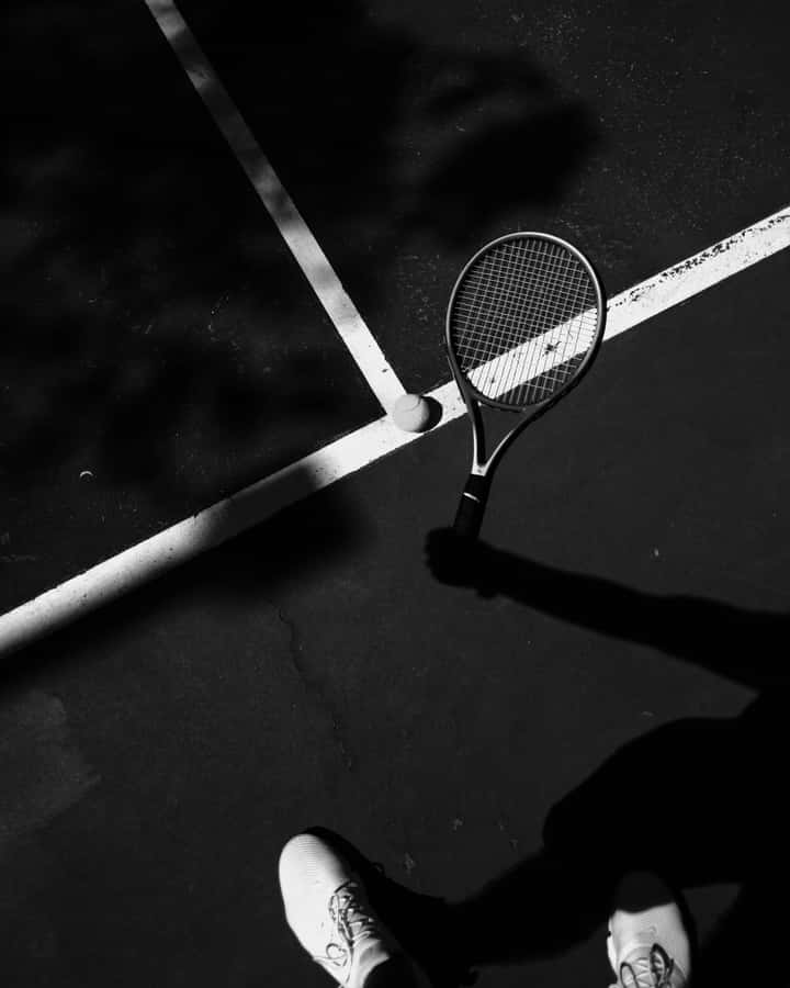 Raquete de Tênis e Bola na Sombra da Quadra