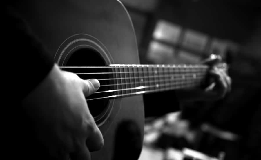 Pessoatocando instrumento musical guitarra em uma imagem preta e branca para papel de parede de computador ou celular.