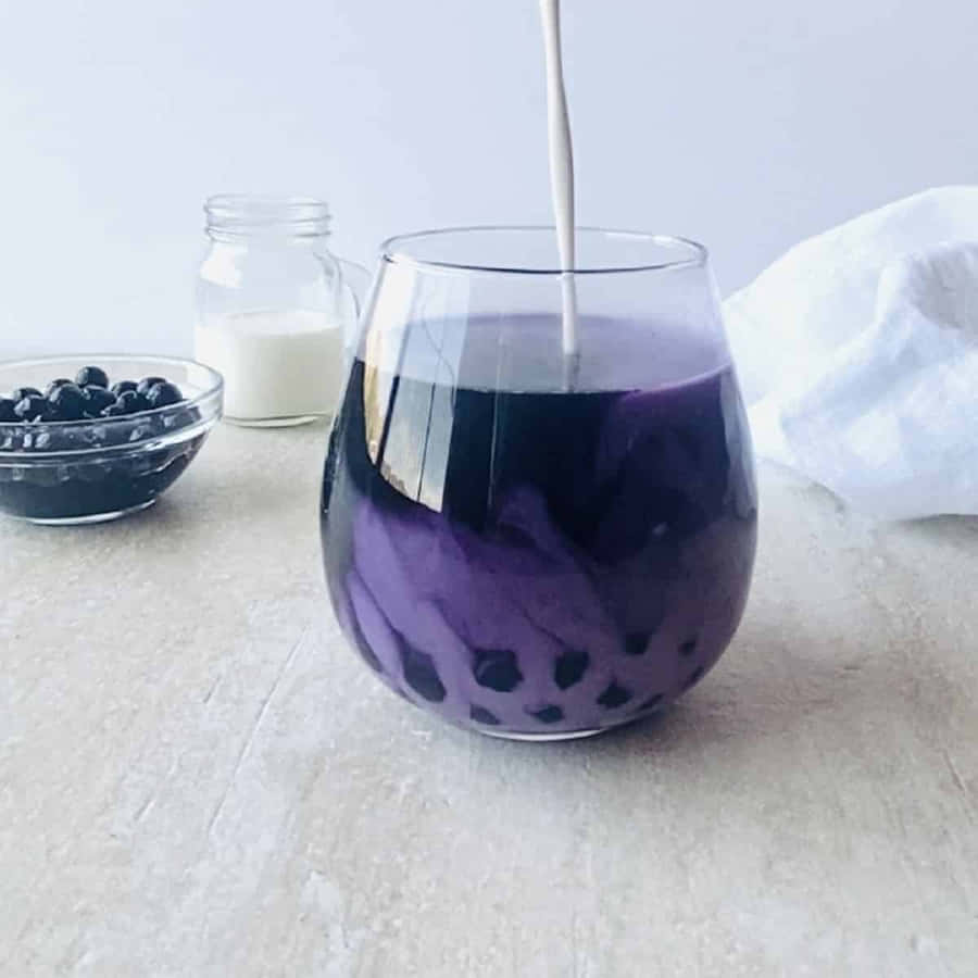 EinGlas lila Milchtee mit Milch.