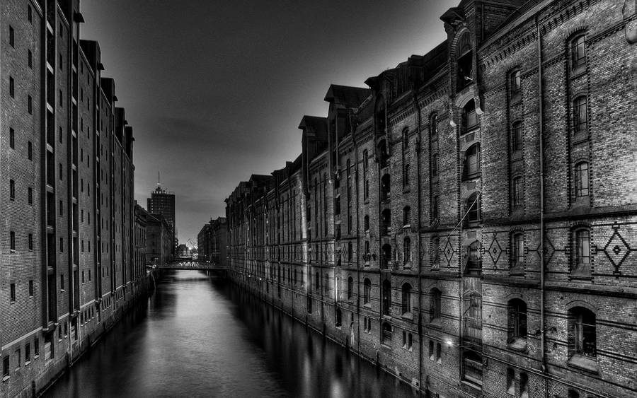 Black and white tall scary buildings surrounding a river during the night.