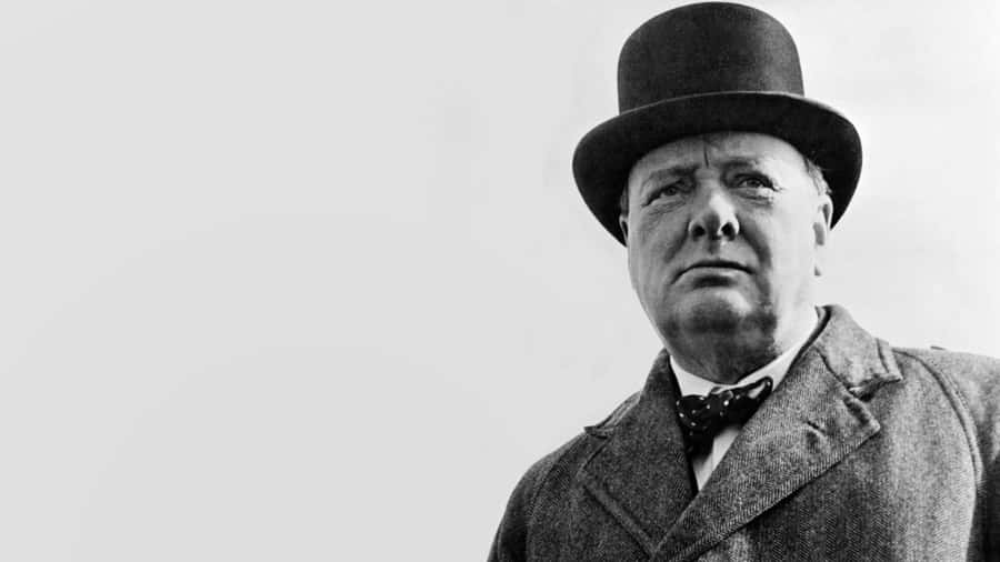 EinMann mit Zylinder steht vor einem schwarz-weiß Foto.