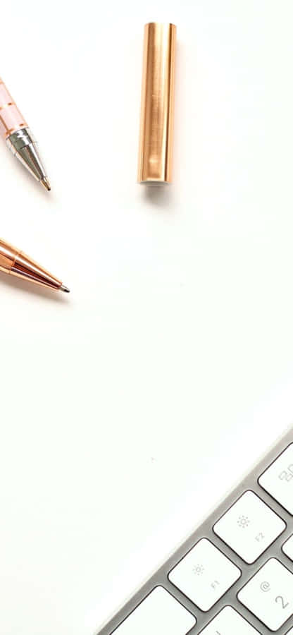 iPhoneX Schreibtisch-Hintergrund: Goldene Stifte neben der Tastatur.