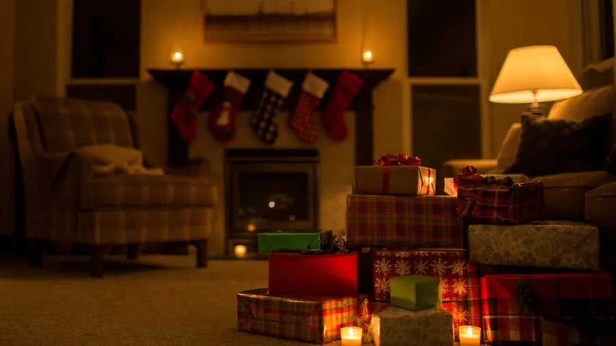 Pile of assorted wrapped gifts in front of a fireplace with stockings.