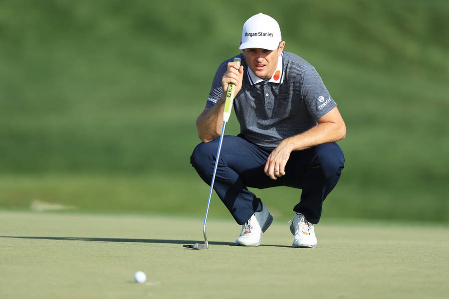 JustinRose schaut sich einen Golfball an, während er in die Hocke geht.