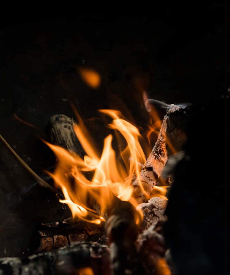 Ettæt billede af ild med stykker af træ og flammer.