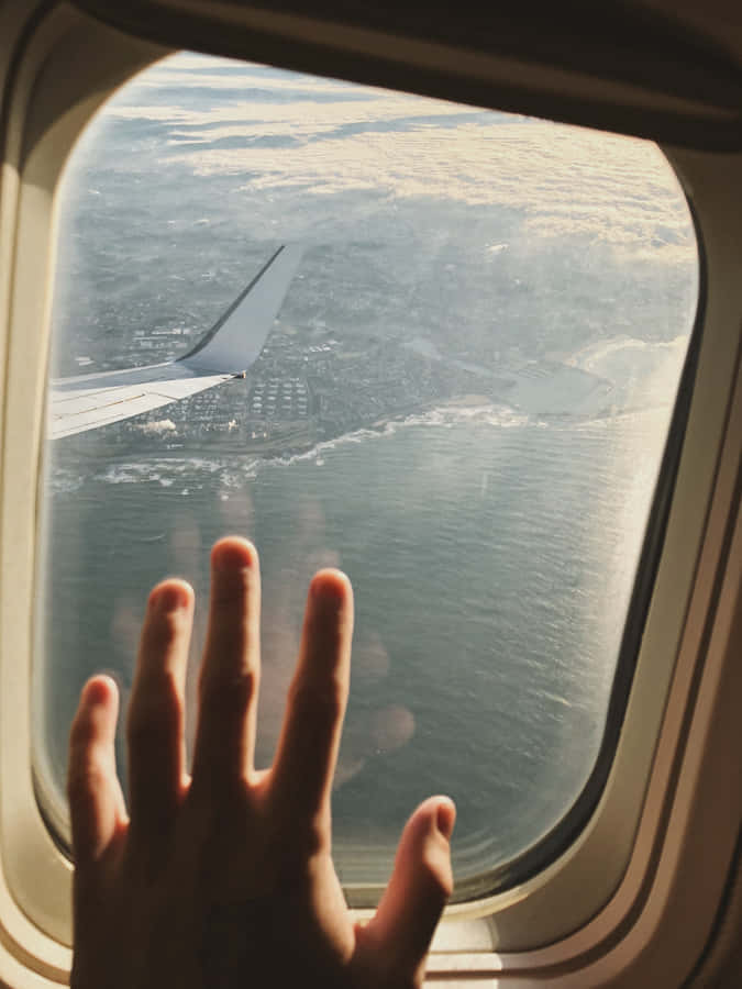 En persons hånd ud af et flyvindu
