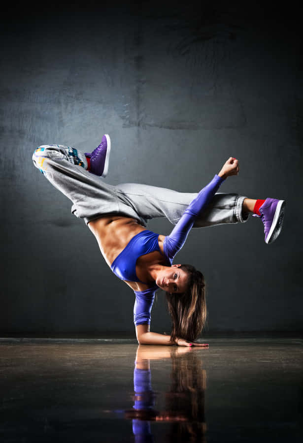 Enkvinde der laver breakdance på en mørk baggrund.