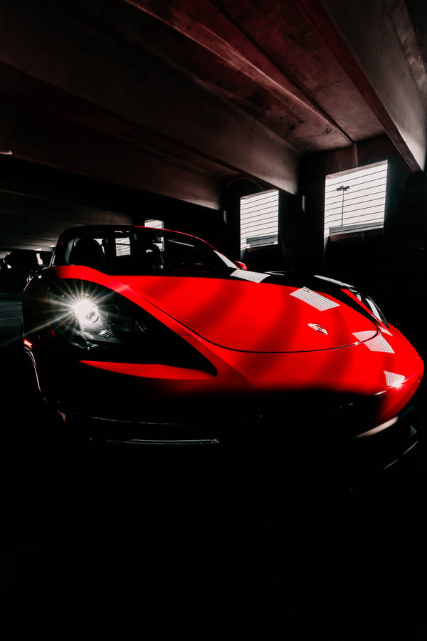 Wallpaper of a red glossy 718 Porsche car in a dark garage.