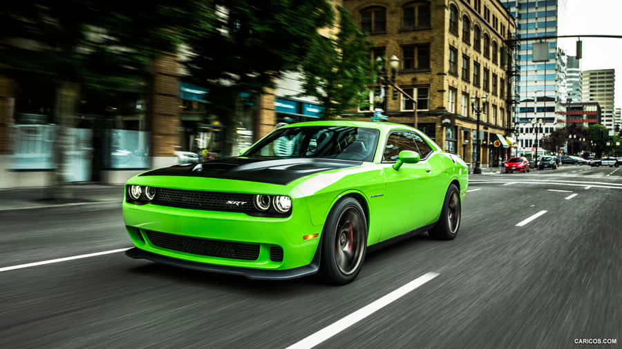 a green dodge challenger driving down a city street Wallpaper