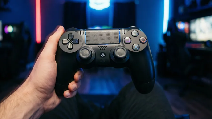 Low angle shot of a person holding a PS4 controller in a neon room.