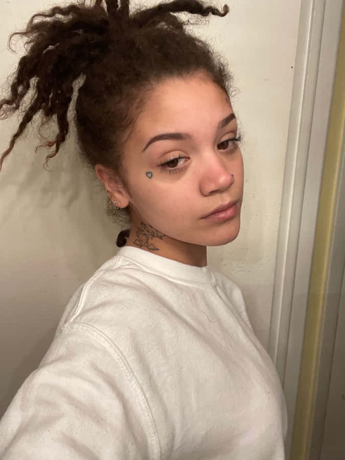 einejunge Frau mit Dreadlocks und Tattoos