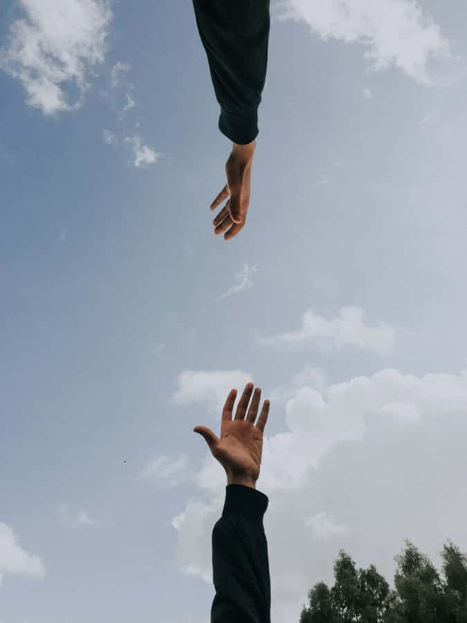 ZweiPersonen strecken sich nach etwas am Himmel aus.