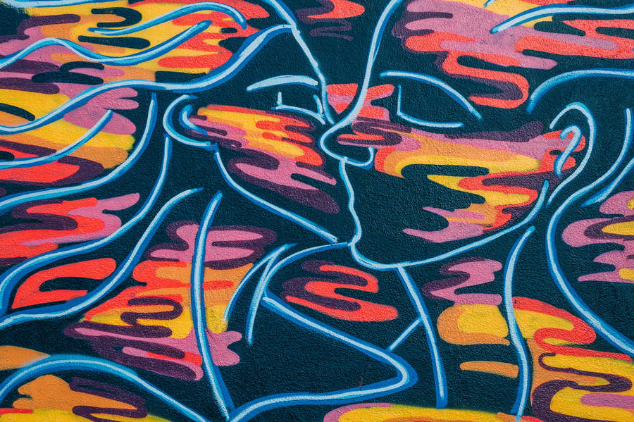 Graffiti art of a man and woman kissing with colorful shapes.