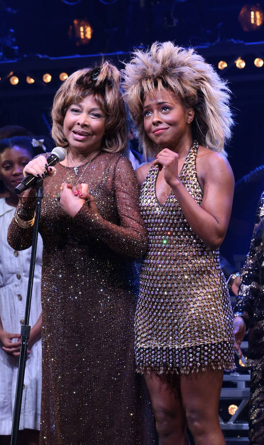 TinaTurner Adrienne Warren sångare Broadway - detta är en beskrivning av en möjlig tapet för en dator eller mobiltelefon om man är ett fan av Tina Turner eller Adrienne Warren, två berömda sångerskor som har spelat huvudrollen på Broadway. Tapeten kan innehålla bilder av sångerskorna eller relaterade grafiska element som passar deras karaktärer och musikstilar. Det skulle vara en perfekt bakgrund för någon som älskar musik och teater!