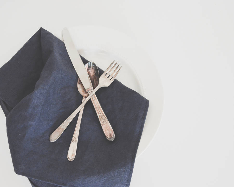 gray fork, spoon, and butter knife on plate with black table napkin