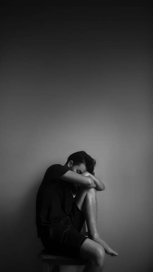 Free Grayscale Photography of Man Sitting Beside Wall Stock Photo