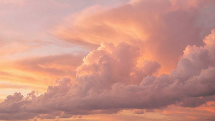Fluffy light pink clouds at sunset, a serene and dreamy sky.
