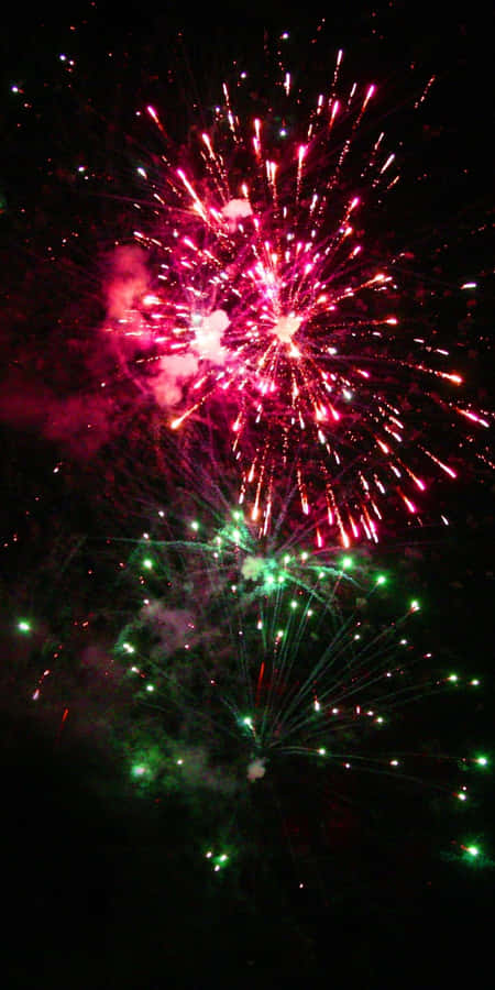 Fundode tela com fogos de artifício verde e rosa cintilante.