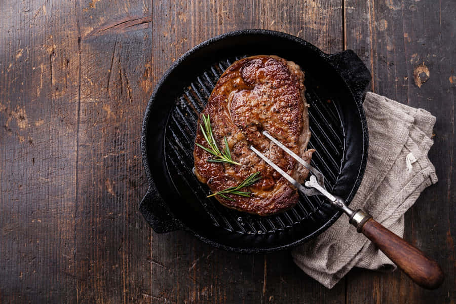 EinSteak wird in einer Gusseisenpfanne gebraten.