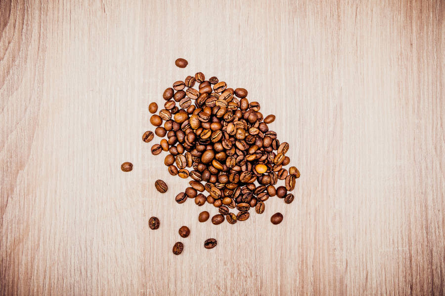 Roasted coffee beans mount on wooden surface wallpaper.