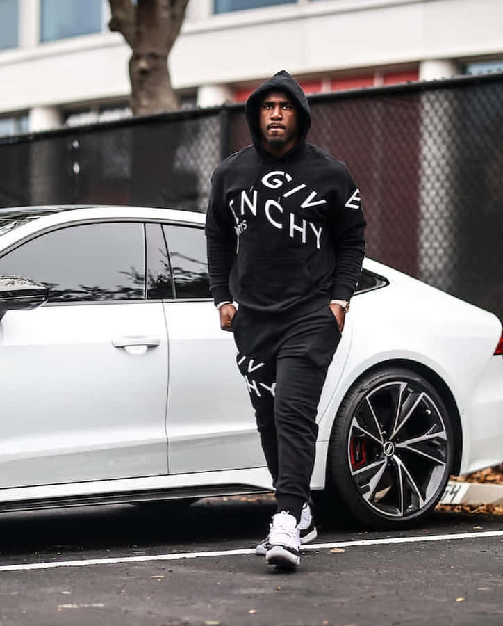 Homem em Moletom Designer e Tênis ao Lado de um Carro