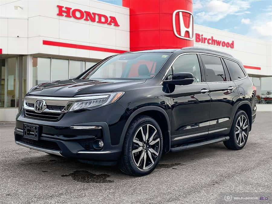 UmHonda Pilot preto está estacionado em frente a uma concessionária Honda.